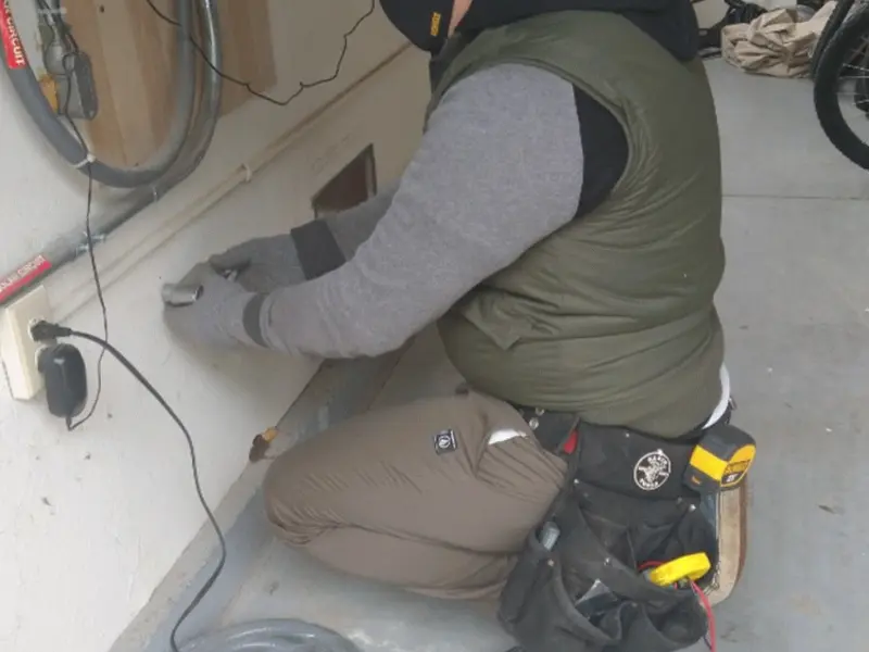Electrician performing outlet wiring in a Acushnet garage